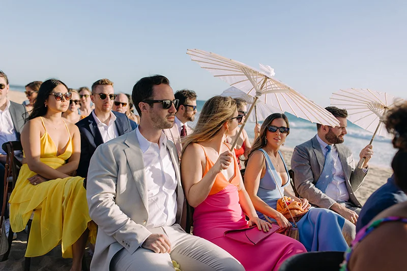 Wedding guests with parasols seated on the sand at Fort Myers Beach