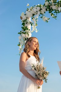 Bride with a bouquet at a white floral arch on Lido Beach