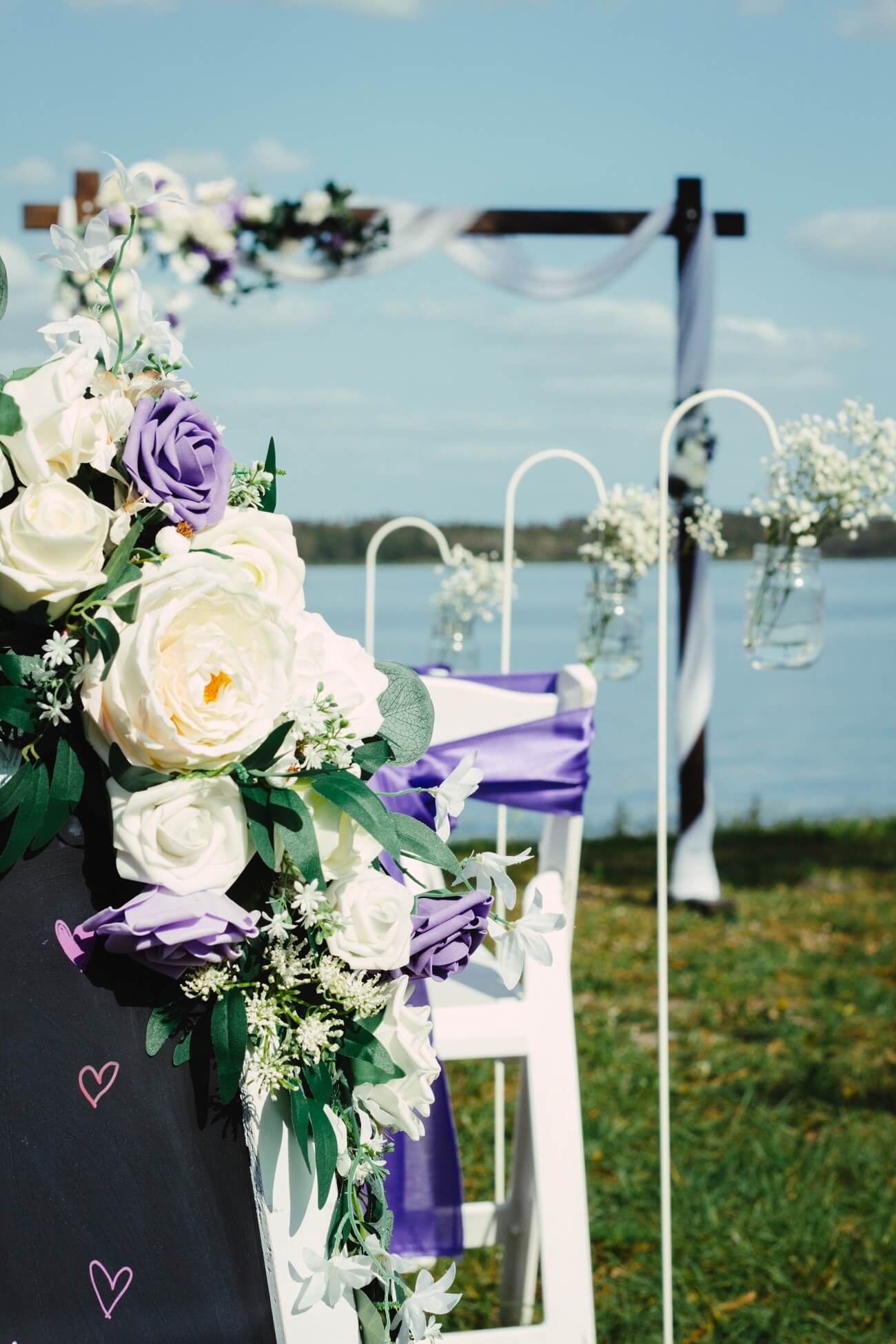 Lakeside garden ceremony with a floral arch and purple-draped chairs