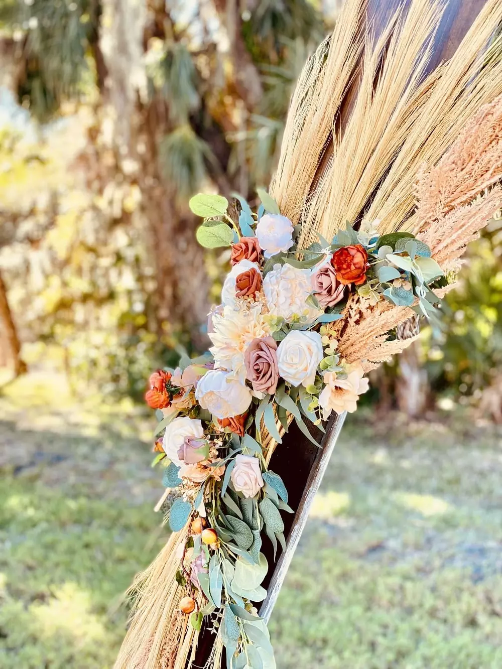 Boho floral arch with pampas grass beneath oak trees in a garden setting