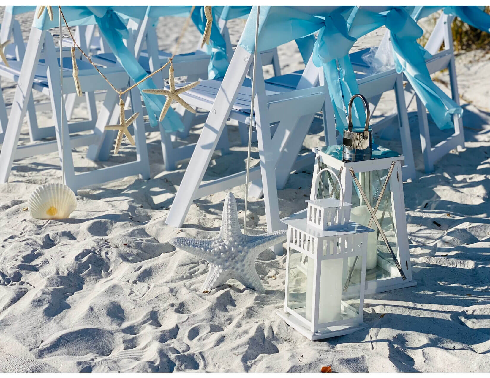 White ceremony chairs with aqua sashes and starfish on the Sarasota-area sand