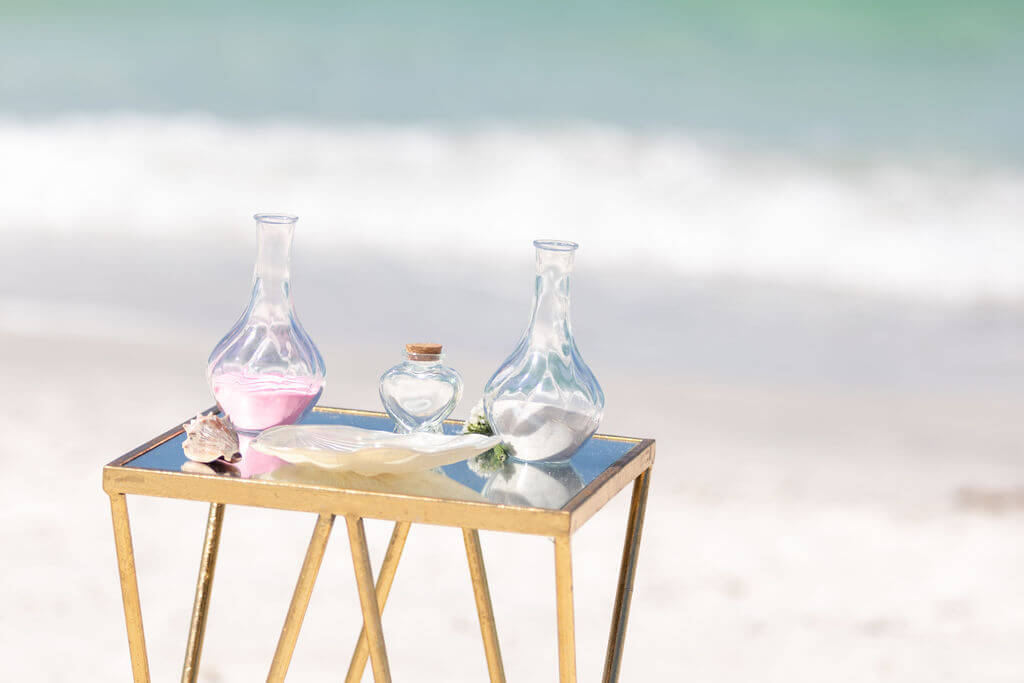 A unity sand ceremony set up on a gold table by the Gulf on Siesta Key