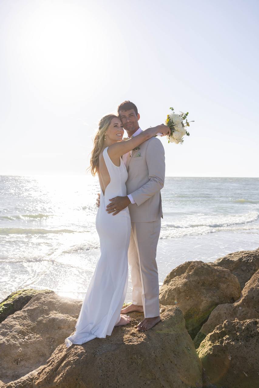 Bride and groom embracing on the rocks at Sunset Beach