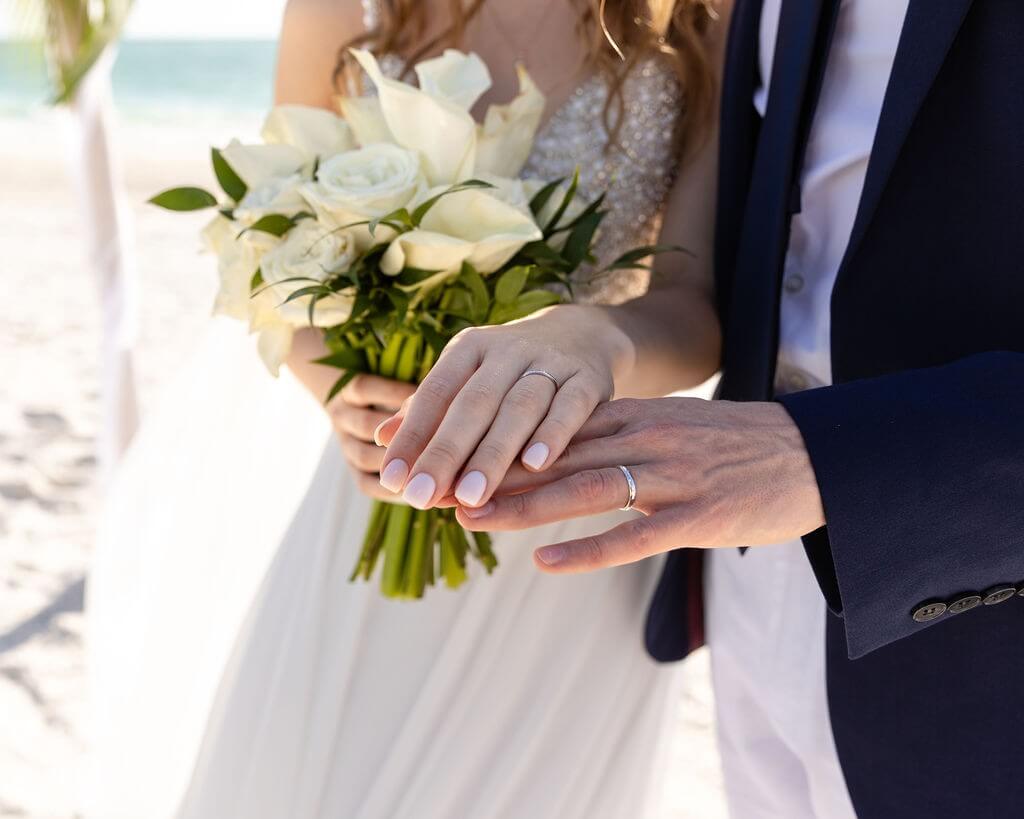 Close-up of the couple's wedding rings and white bouquet on Treasure Island Beach