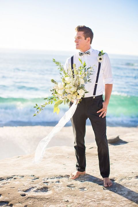 Barefoot groom in a bow tie and suspenders with a greenery bouquet on Venice Beach