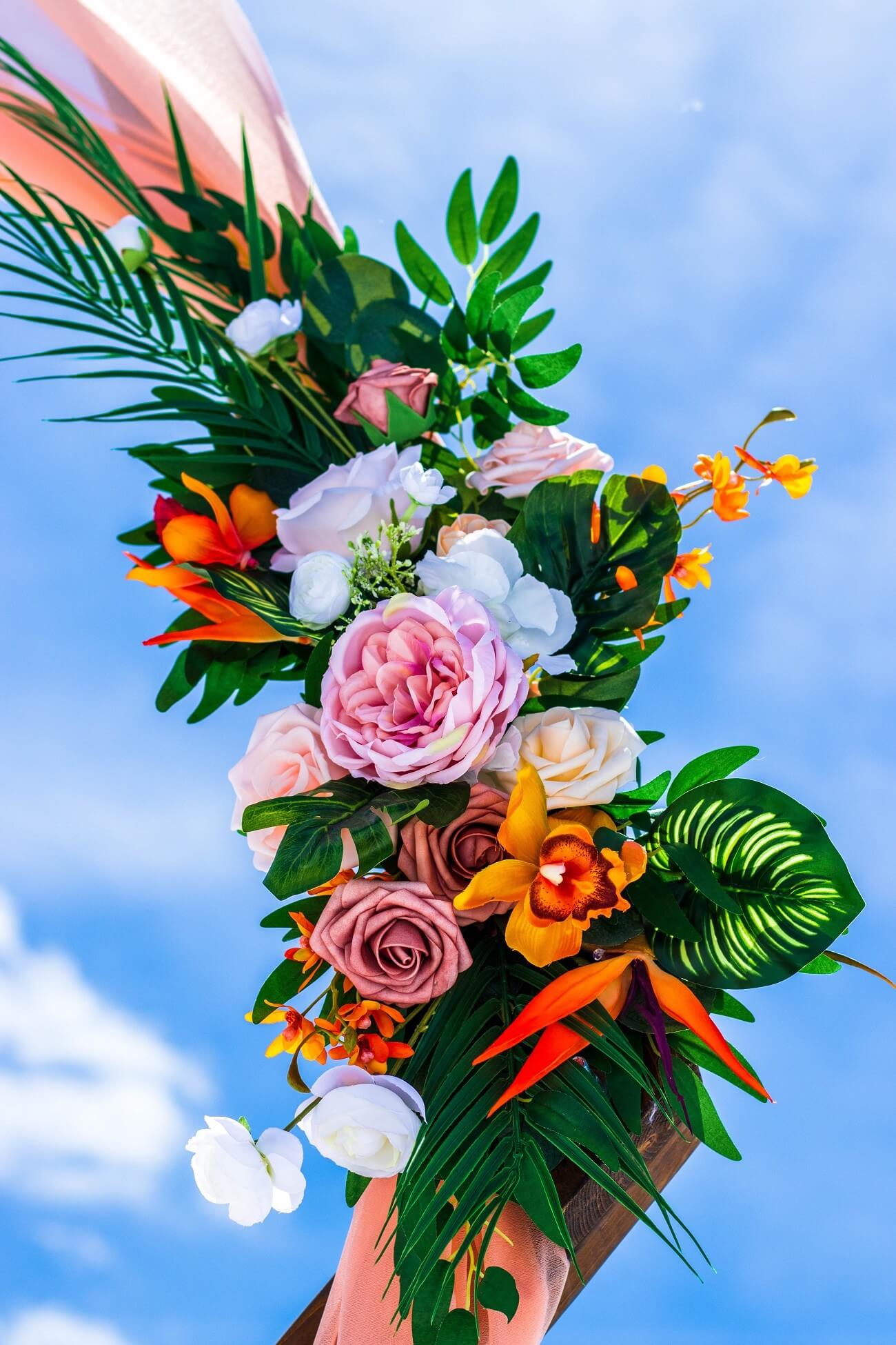 Vibrant tropical floral arch arrangement against a blue sky on Venice Beach