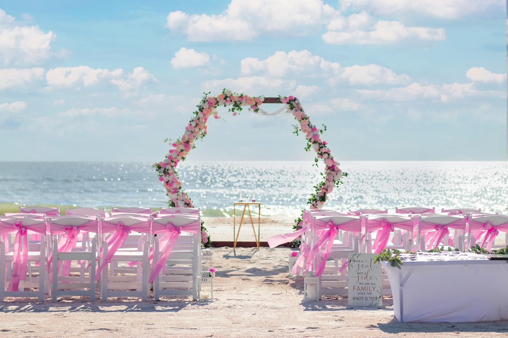 Boho beach arch adorned with a cluster of rust and blush roses with eucalyptus — the Forever Bliss package
